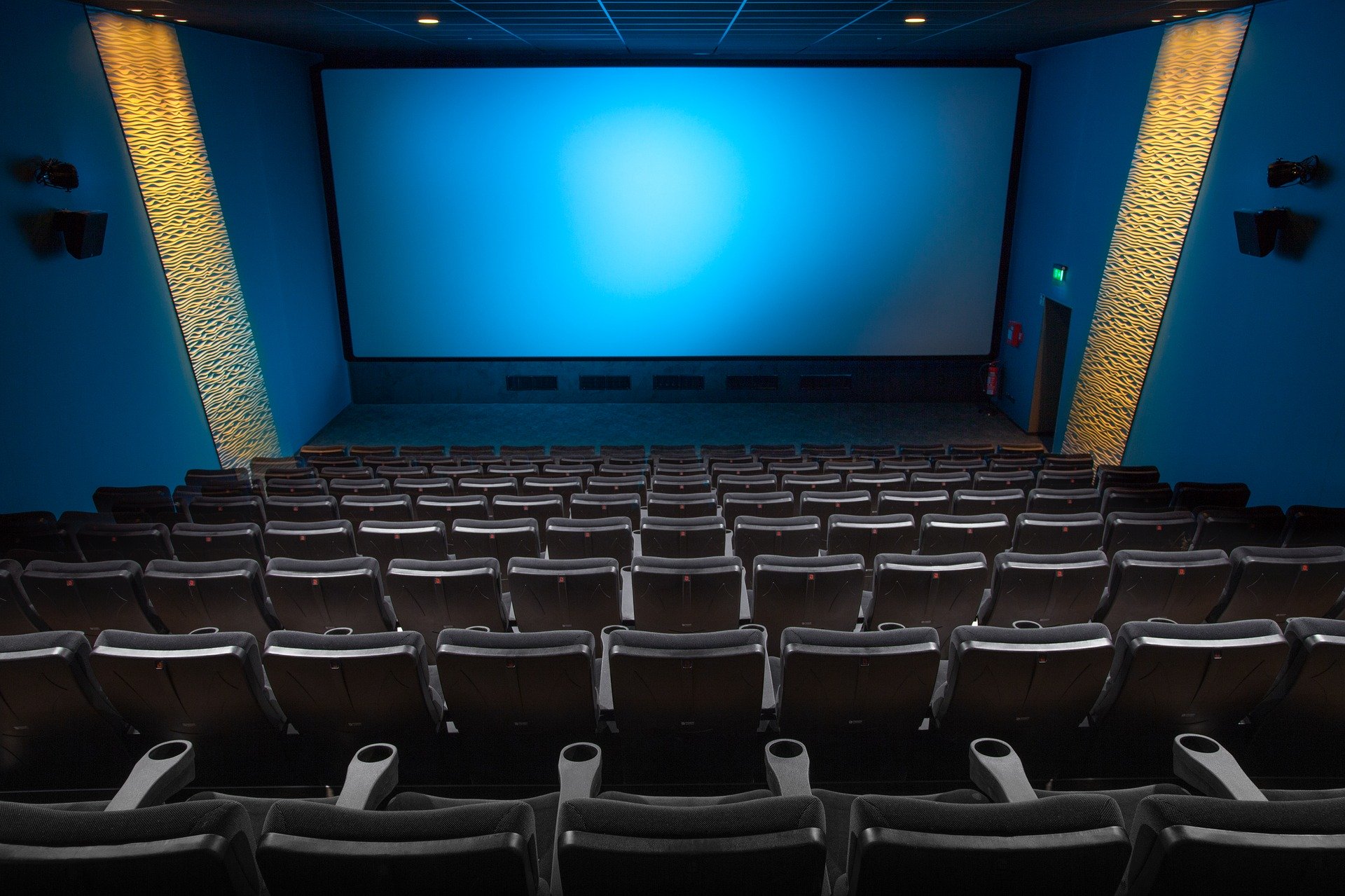 A small movie theater lit in blue with bold panels on the side walls | gtg