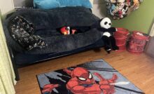 Image of green boys room with brown vinyl plank flooring, Spider-man rug, and futon.